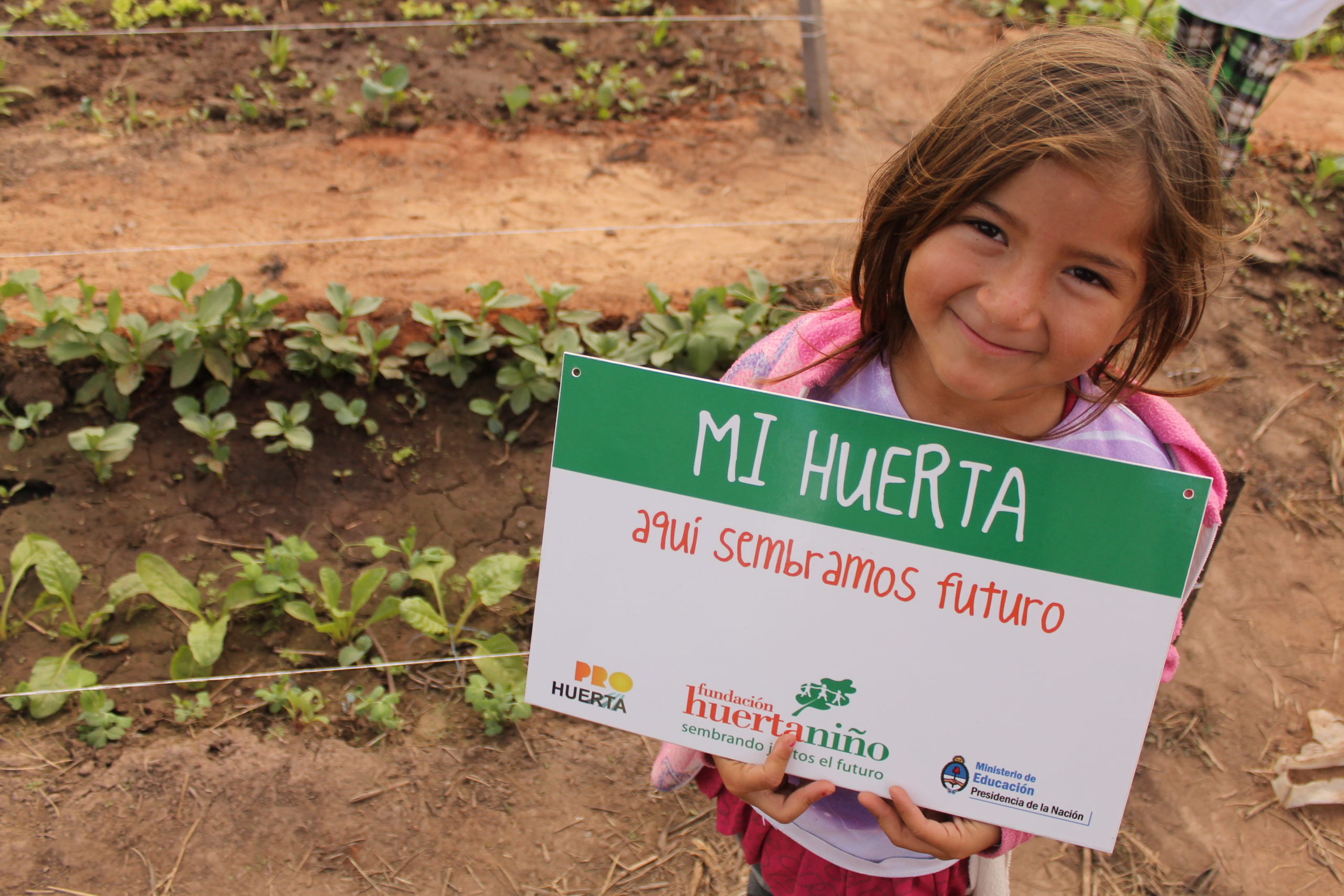 Niña y cartel de huerta